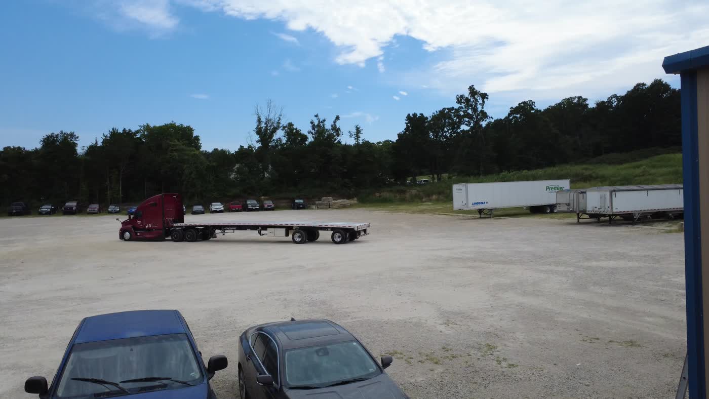 Drone view of the Tipton Hay Farms yard in Marshfield, Missouri — a Kenworth and flatbed on the gravel lot
